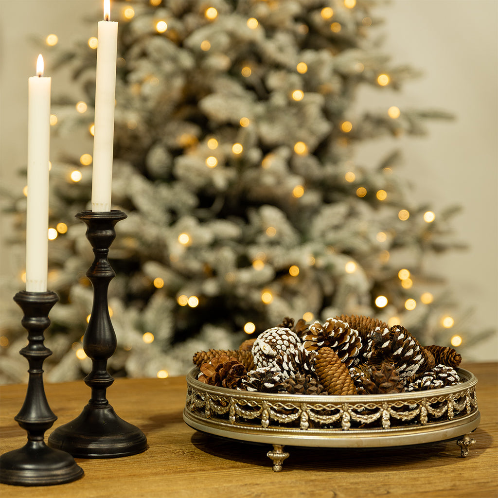 A gold mirror tray filled with pinecones for Christmas.