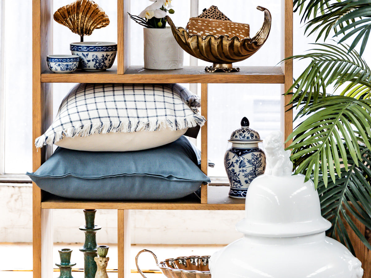 Decorative shelf with pillows, vases, and a plant