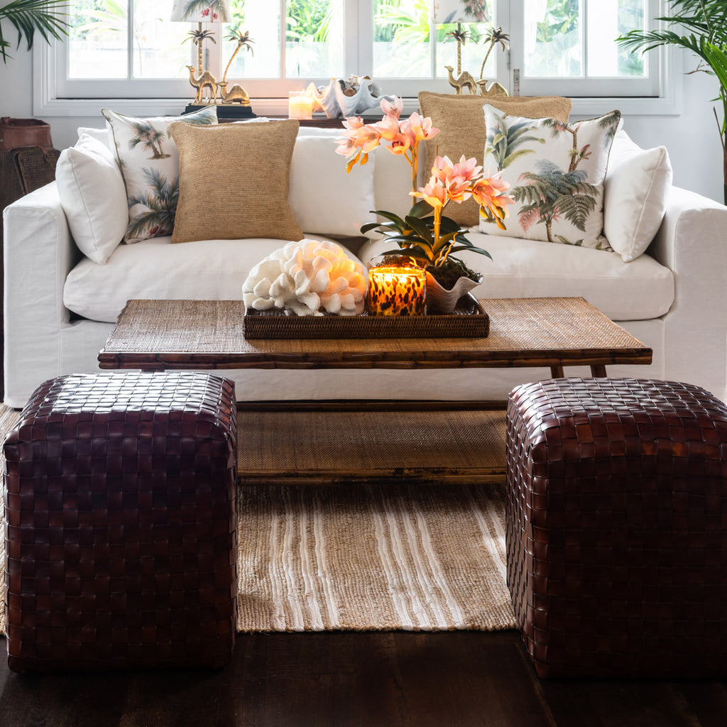 two leather woven ottomans next to a coffee table opposite a sofa