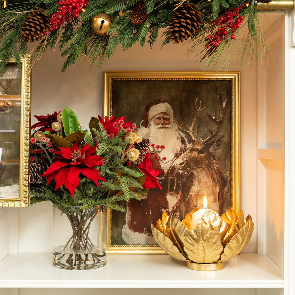 Red poinsettia arrangement on a white bookshelf next to Santa Claus print.