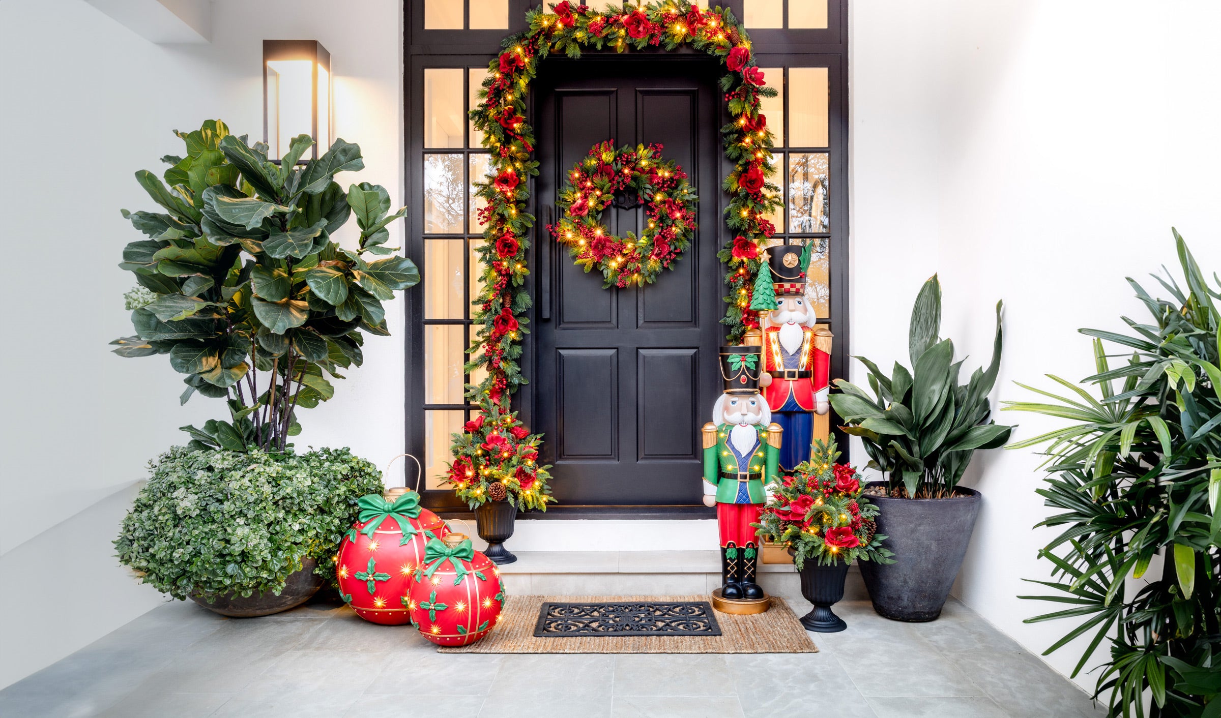 Decorative front porch with Christmas wreaths, nutcrackers, and potted plants.