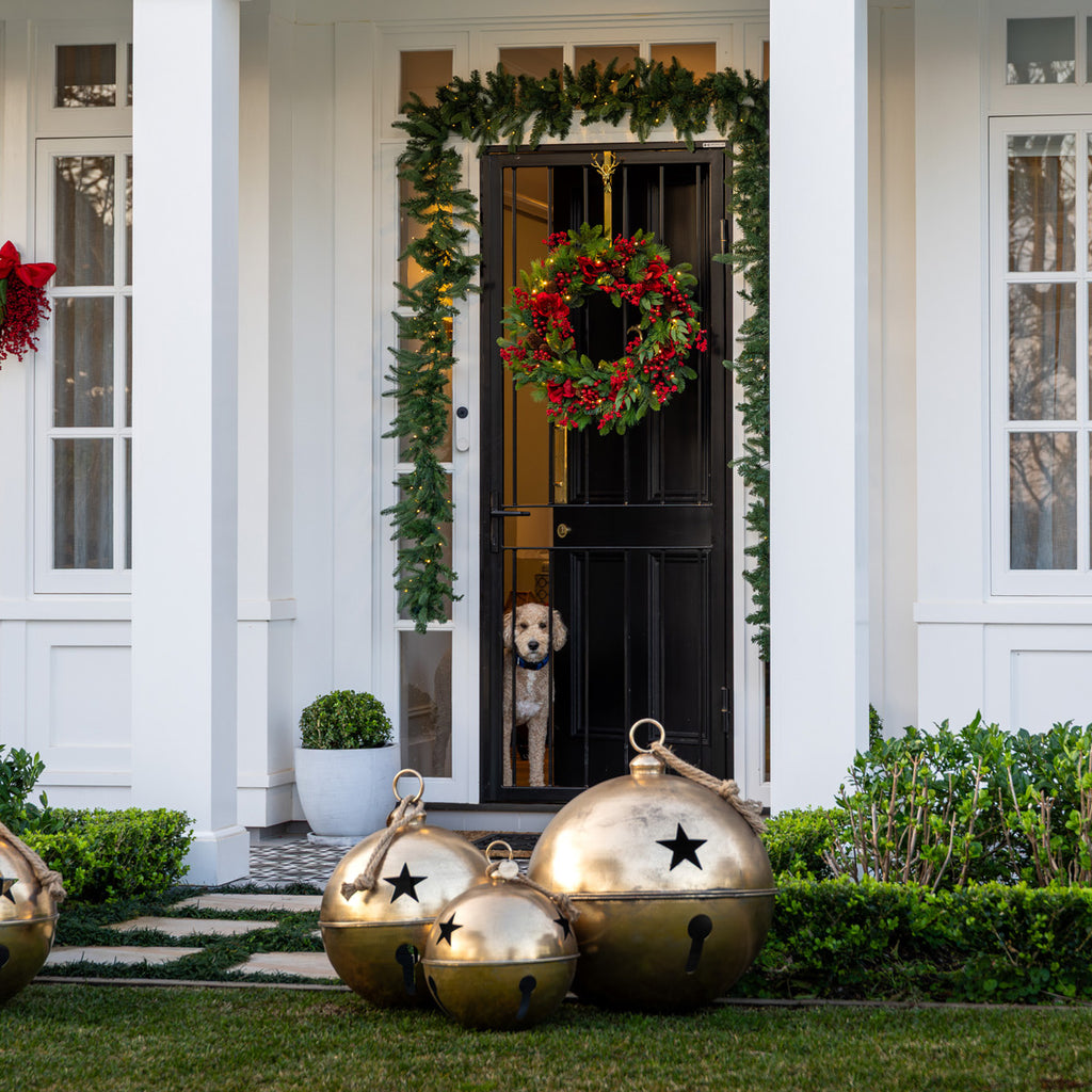 Front door of a house decorated for Christmas with wreaths and gold jingle bells.