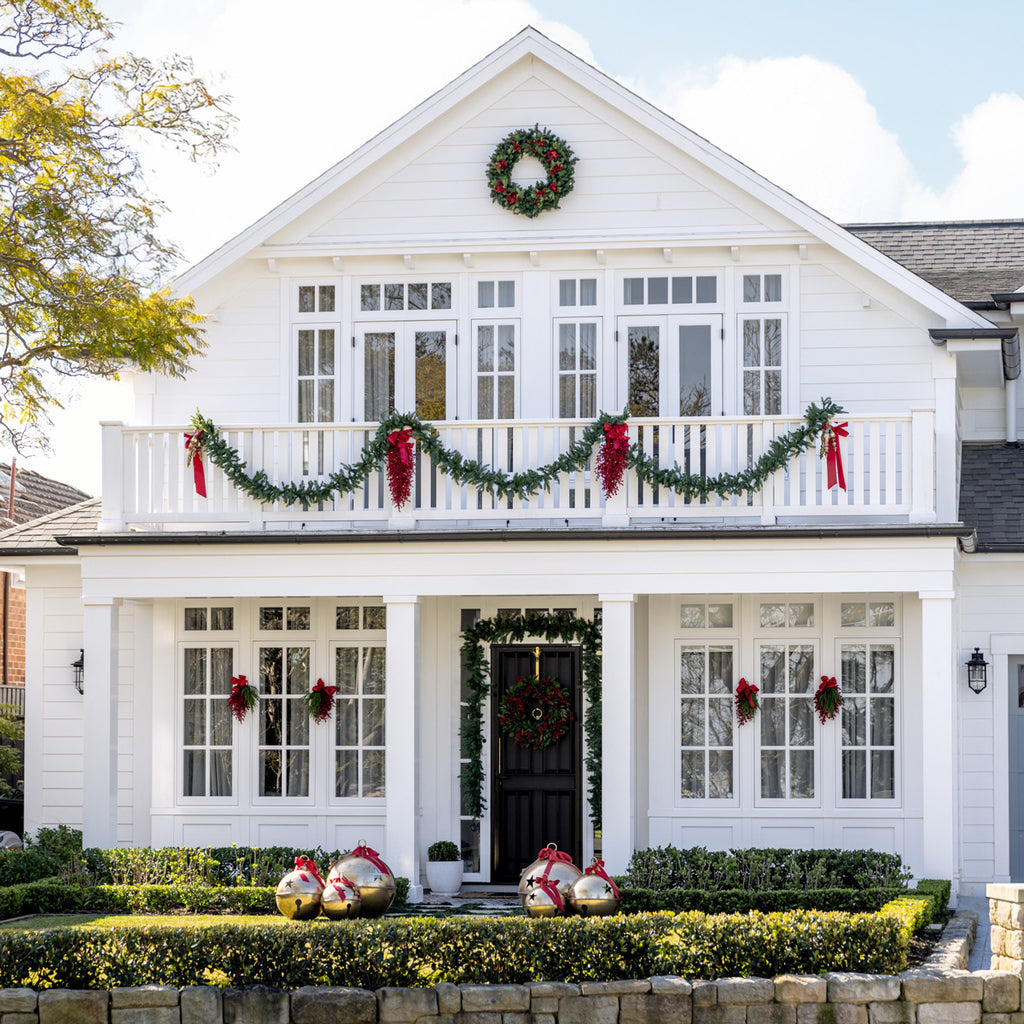 White house decorated with Christmas garlands, wreaths, and ornaments.