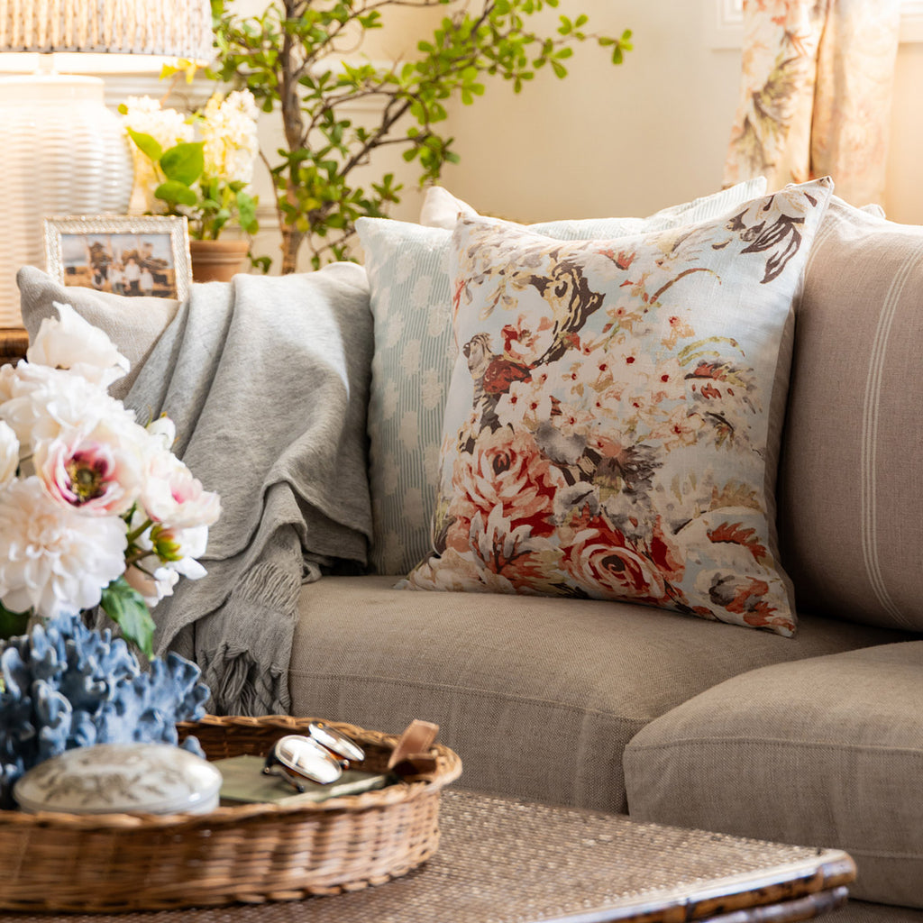 Decorative living room with floral pillow on a sofa, flowers, and a basket.