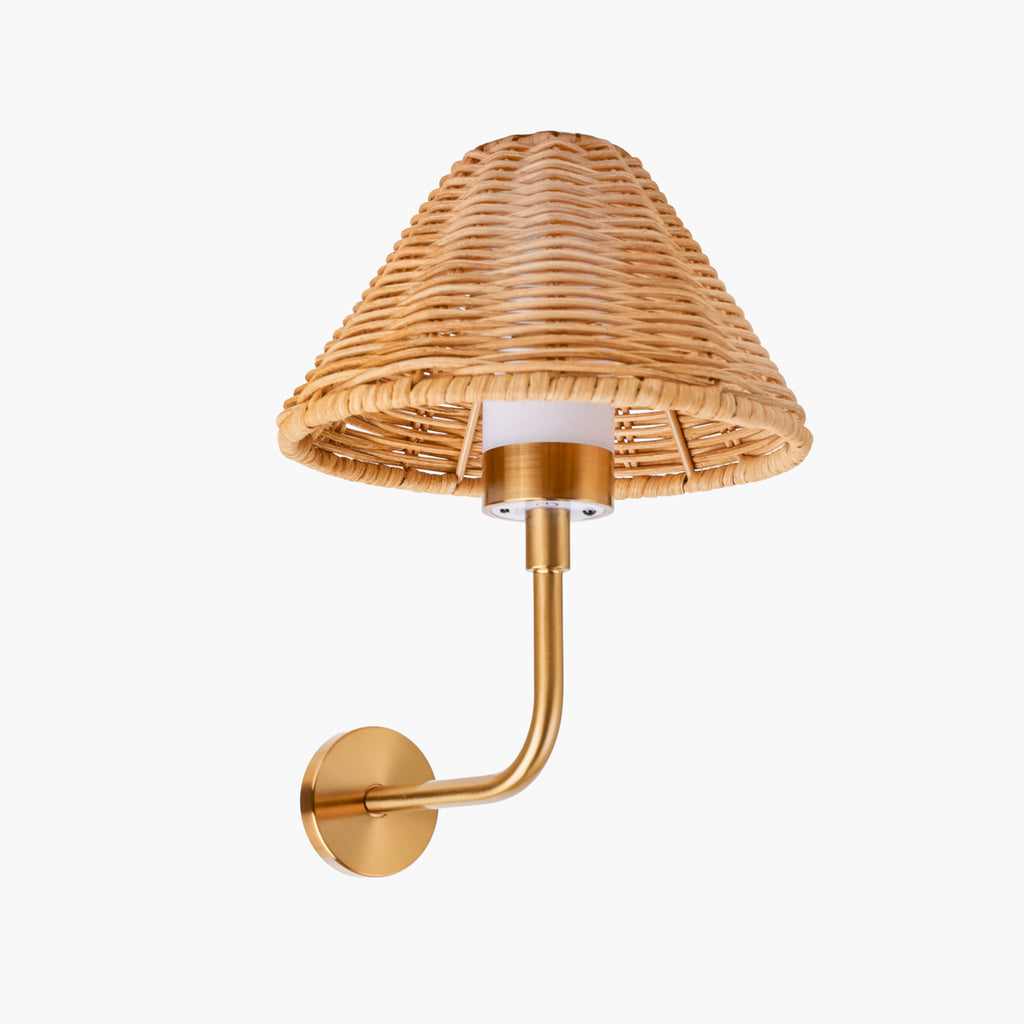 A wall-mounted sconce with a natural woven rattan shade and a brushed brass/gold metal arm and wall plate, shown against a plain light gray background.