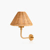 A wall-mounted sconce with a natural woven rattan shade and a curved brass metal arm and wall plate, shown against a plain white background.
