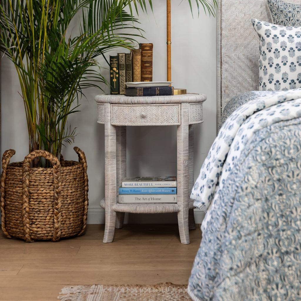 Rattan Round Side Table (White Washed) Styled in Bedroom with Books and Plant next to it
