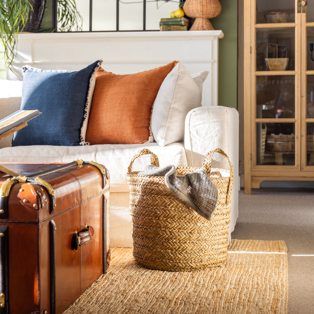 Sapa Woven Seagrass Baskets Styled Next to Sofa with Blanket Inside