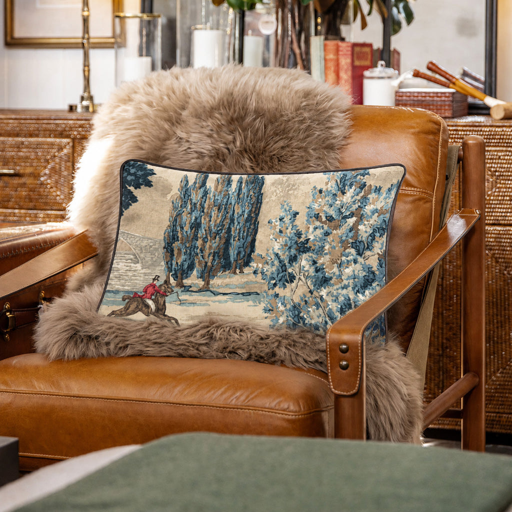Decorative pillow with a landscape design on a brown leather armchair.