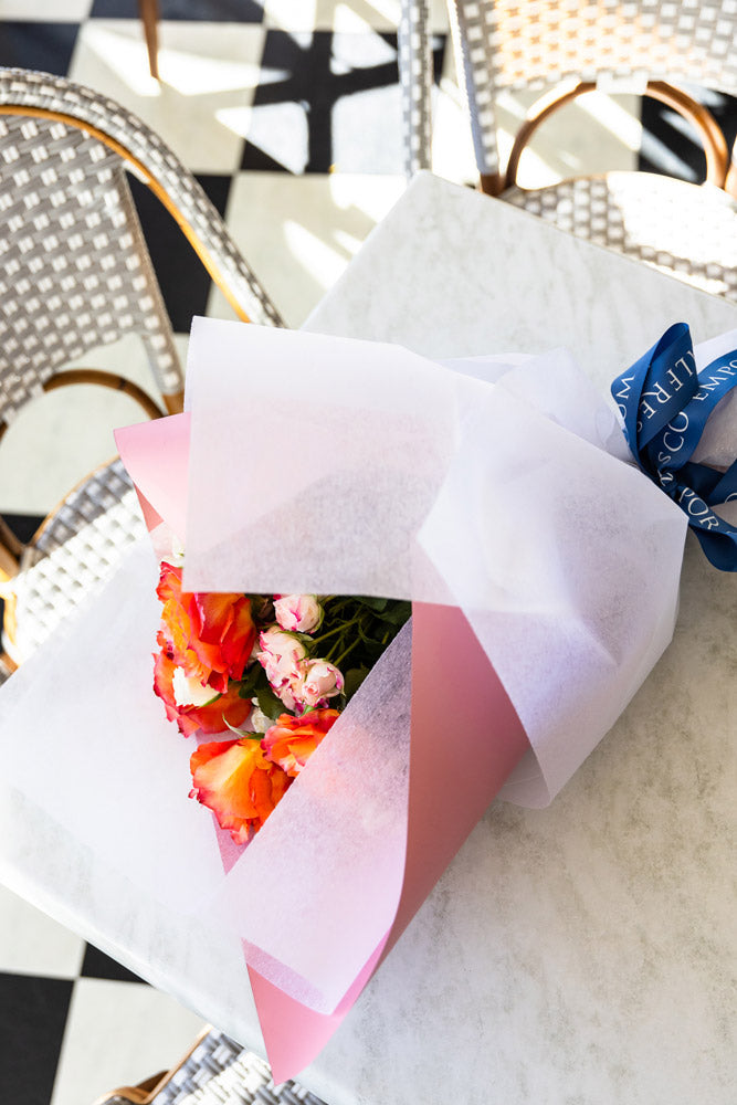 A bouquet of roses tied with Alfresco Emporium ribbon.