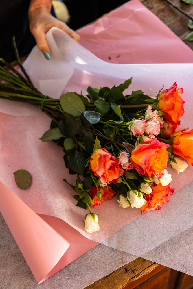 A bouquet of roses being wrapped.