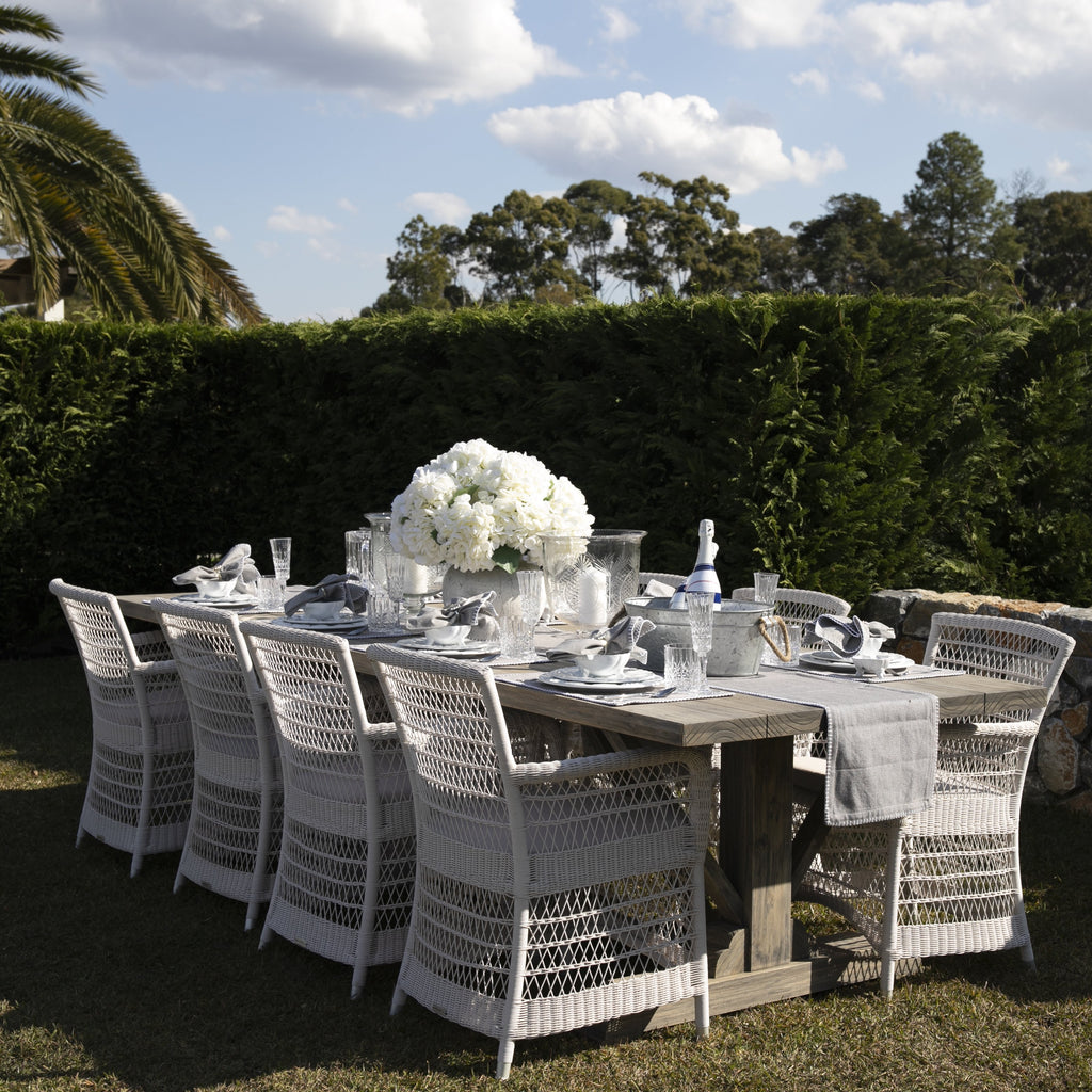 Hampton Outdoor Dining Chairs in white around a table in a garden